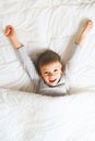 Cheerful little boy in bed with alarm clock, wake up morning concept, sleeping time Royalty Free Stock Photo
