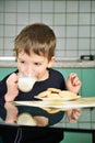 Cheerful little boy drinking milk, sitting at the dinner table. Royalty Free Stock Photo