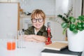 Cheerful little boy in glasses sitting behind the table in front microscope Royalty Free Stock Photo
