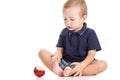 Cheerful little boy with red apple is smiling, sitting on a floor, isolated white Royalty Free Stock Photo