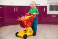Cheerful little boy with shopping cart. Little kid in casual wear carrying child plastic shopping trolley. Shopping, discount, Royalty Free Stock Photo