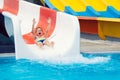 Cheerful little boy sliding into water in aqua park Royalty Free Stock Photo