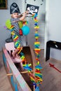 A cheerful little child in a pirate costume plays at home on a cardboard sea ship with a black flag. Fun games at home with family Royalty Free Stock Photo