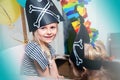 A cheerful little child in a pirate costume plays at home on a cardboard sea ship with a black flag. Fun games at home with family Royalty Free Stock Photo
