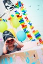 A cheerful little child in a pirate costume plays at home on a cardboard sea ship with a black flag. Fun games at home with family Royalty Free Stock Photo