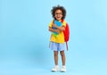 Cheerful little ethnic schoolchild with backpack and textbooks in studio Royalty Free Stock Photo