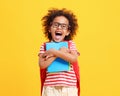 Cheerful little ethnic schoolchild with backpack and textbooks in yellow studio Royalty Free Stock Photo