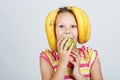 Cheerful little girl with apples, lemon and banana poses positively in studio