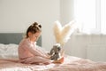 A cheerful little girl on the bed after waking up plays with her toy elephant Royalty Free Stock Photo