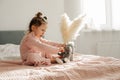 A cheerful little girl on the bed after waking up plays with her toy elephant Royalty Free Stock Photo