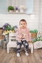 Cheerful little girl child one year old sits on bench on veranda. spring summer time. nature pastime concept