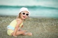 Cheerful little girl with Down syndrome with glasses resting on the sea coast Royalty Free Stock Photo