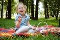 Cheerful little girl eating strawberries at picnic in park, sitting on green grass and smiling. Summer holidays and recreation Royalty Free Stock Photo