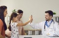 Cheerful little girl giving five to positive young man doctor pediatrician Royalty Free Stock Photo