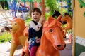 Cheerful little girl goes for a drive on a roundabout in the amusement park of the city