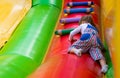 A cheerful little girl is having fun on a high inflatable game slide. A little baby is playing on an inflatable trampoline on a fe Royalty Free Stock Photo