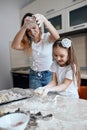 Cheerful little girl and her mother throwing flour on the table Royalty Free Stock Photo