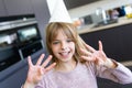 Cheerful little girl holding up eight fingers while celebrating her birthday in the kitchen at home