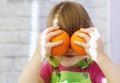 A cheerful little girl holds fresh oranges to her face. Portrait of a funny cute girl holding oranges to her eyes. The Little baby Royalty Free Stock Photo