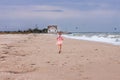 Cheerful little girl with long blonde hair in pink tulle skirt walking empty sea beach alone. Beautiful little princess Royalty Free Stock Photo