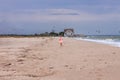 Cheerful little girl with long blonde hair in pink tulle skirt walking empty sea beach alone. Beautiful little princess Royalty Free Stock Photo