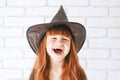 A cheerful little girl with long red hair is smiling in a witch costume for Halloween.A cute little girl with a toothless smile in