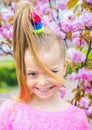 Cheerful little girl looking at a camera in park. Blooming cherry. Beautiful young kid girl with speaking look. Adorable