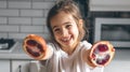 Cheerful little girl with oranges in the kitchen interior. Royalty Free Stock Photo