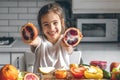 Cheerful little girl with oranges in the kitchen interior. Royalty Free Stock Photo