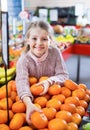 Cheerful little girl purchasing sweet mandarines