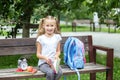 A cheerful little girl is reading a book on a bench. The concept of school, study, education, friendship, childhood. Royalty Free Stock Photo