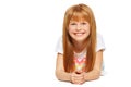 A cheerful little girl with red hair is lying; isolated on the white background Royalty Free Stock Photo