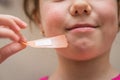 A cheerful little girl removes a sticky patch from her skin. Children`s mouth close-up.Child pulling the plaster off his face Royalty Free Stock Photo