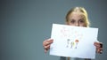 Cheerful little girl showing family picture into camera, feeling parental love