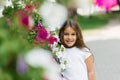 Cheerful little girl smiles among the flowers in summer Royalty Free Stock Photo