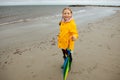 Cheerful little girl staying on beach with colorful ambrella on Baltic sea at rainy wether Royalty Free Stock Photo