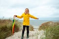 Cheerful little girl staying on beach with colorful ambrella on Baltic sea at windy weathe Royalty Free Stock Photo