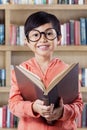 Cheerful little girl studying with book in library Royalty Free Stock Photo