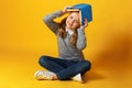 A cheerful little student girl is sitting on the floor with a book on her head. Education and school concept Royalty Free Stock Photo