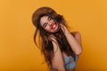 Cheerful long-haired girl with trendy makeup enjoying good day and happy smiling. Studio shot of easygoing young woman