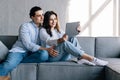 Cheerful lovely couple cuddling on sofa at home, using digital tablet for websurfing, free space Royalty Free Stock Photo