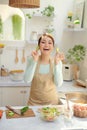 Cheerful lovely young housewife having fun during cooking in kitchen