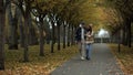 Cheerful lovers walking happily along alley in foliage park. Beautiful couple.