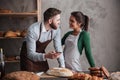 Cheerful loving couple bakers holding mobile phone.