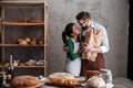 Cheerful loving couple bakers standing near bread