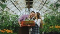 Cheerful loving couple gardeners taking selfie picture on smartphone camera while working in greenhouse