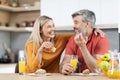 Cheerful man and woman having snack and talking at home