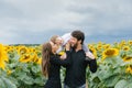 Cheerful loving young family with their son on vacation in a field with sunflowers