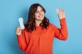 Cheerful magnetic cute dark haired woman holding menstrual cup and sanitary pad in both hands, looking hygiene product with smile Royalty Free Stock Photo