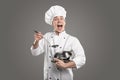 Cheerful male cook with saucepan and soup ladle